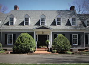 Traditional gray house with steep roof and dormer windows under clear sky