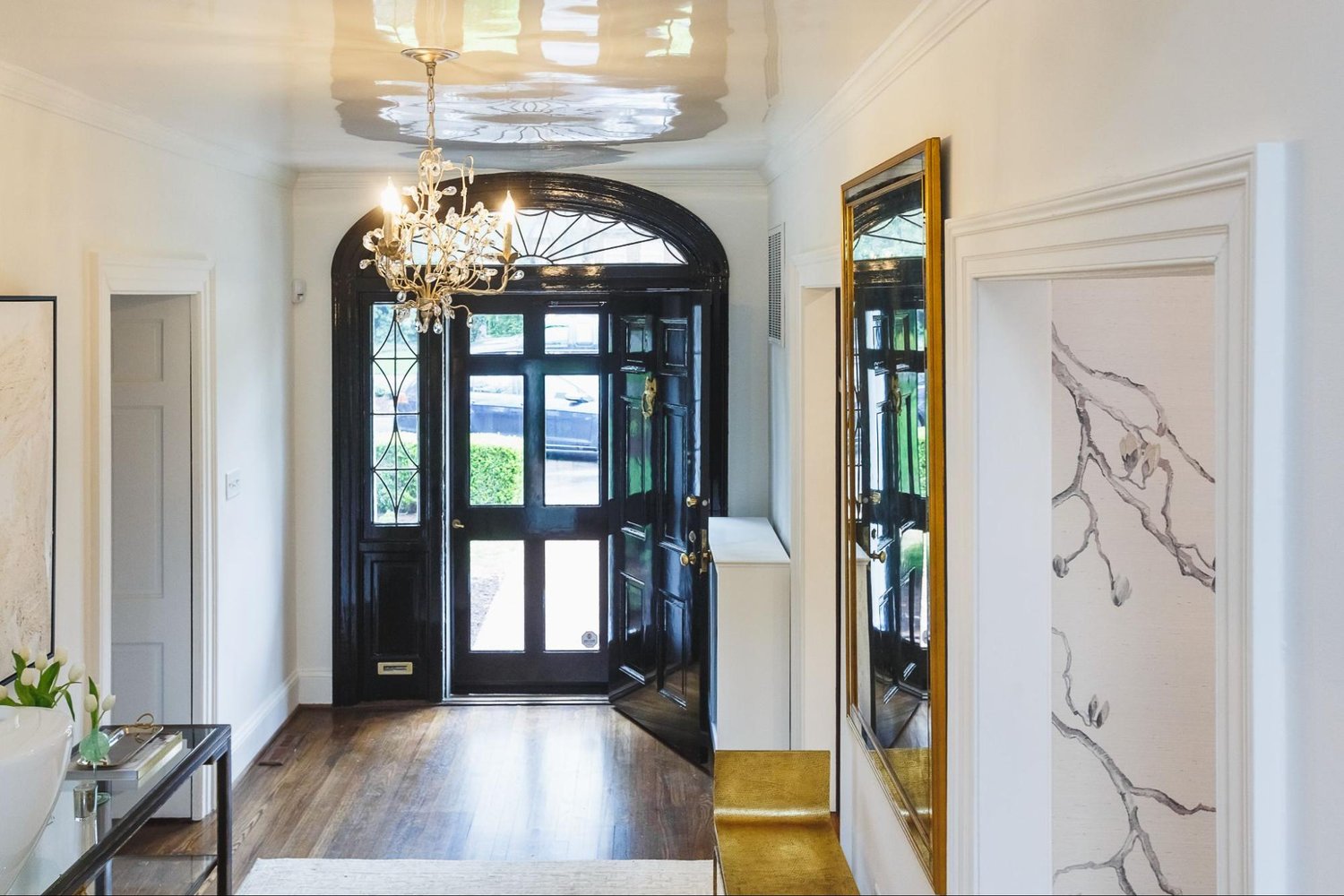 Elegant modern home entrance with chandelier and black door