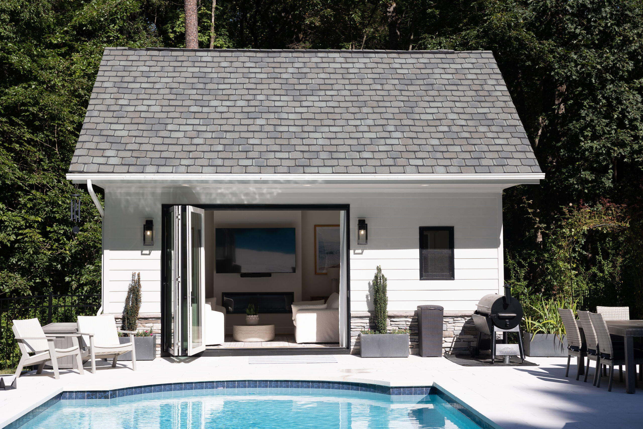 view of pool house from pool with tri fold doors open
