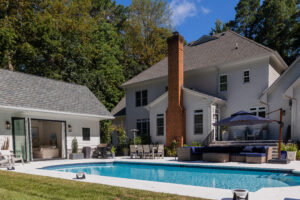 view of pool house with existing home and pool