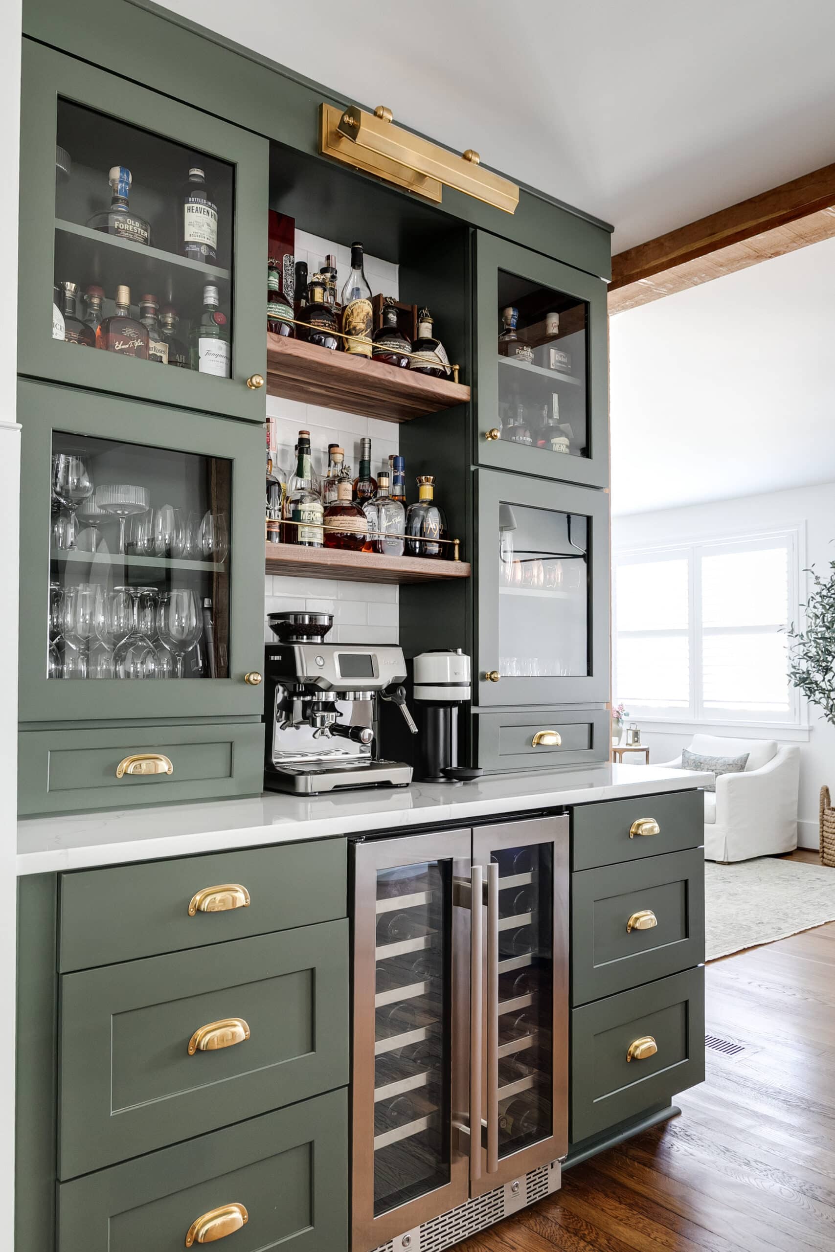 Stunning deep green custom built home bar with brass hardware and accent lighting